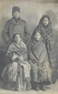 Photograph from 1910 of a Ho-Chunk family: an elderly woman and her daughter are seated; the daughter's son and his wife are standing behind them