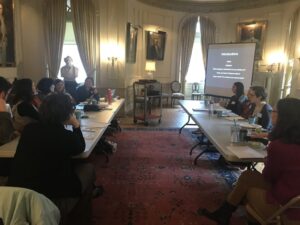 Two groups of people sitting at long tables watching a slideshow