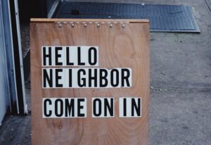 Sandwich board that reads "Hello neighbor, come on in"