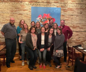 WiLS staffers standing in front of a brick wall and blue painting