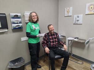 A nurse and patient smile at the camera during a screening